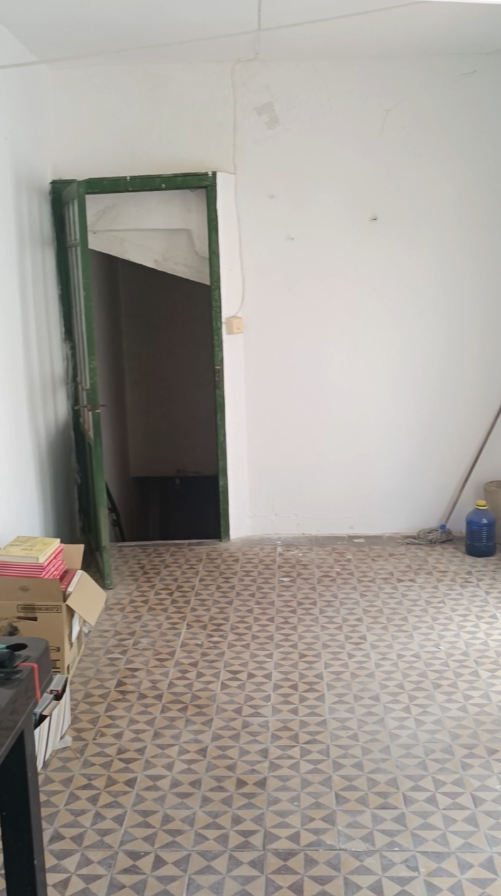 Estancia vacía con suelo de baldosa y puerta verde antes de redistribuir