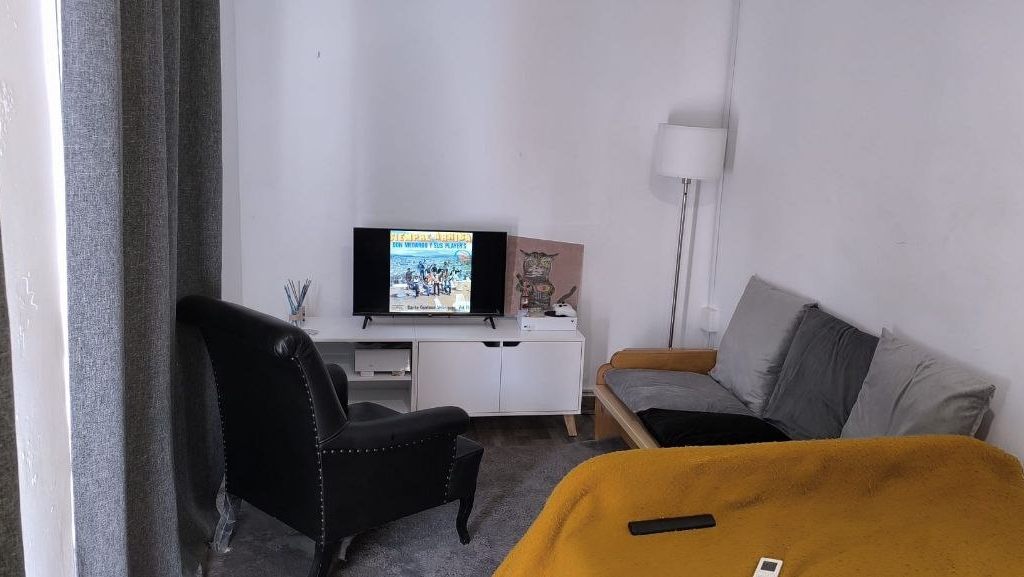 Habitación con ventanales convertida en zona de trabajo y sofá cama