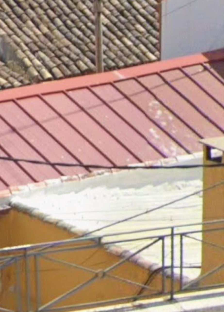 Encuentro de cubierta reparado con impermeabilización roja y remate blanco