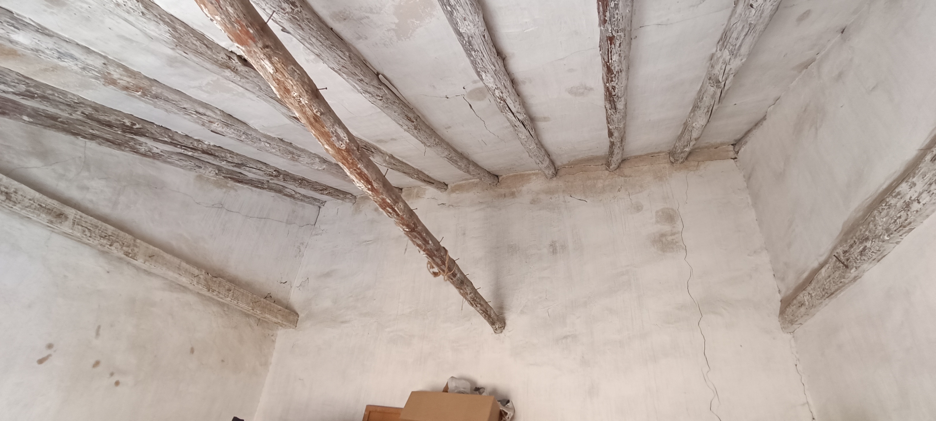 Techo de habitación con vigas antiguas y manchas antes del arreglo