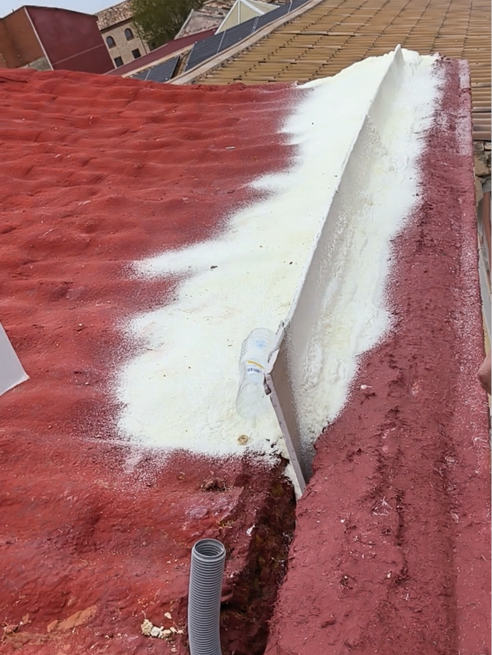 Tejado reparado con capa impermeable roja y banda blanca de refuerzo