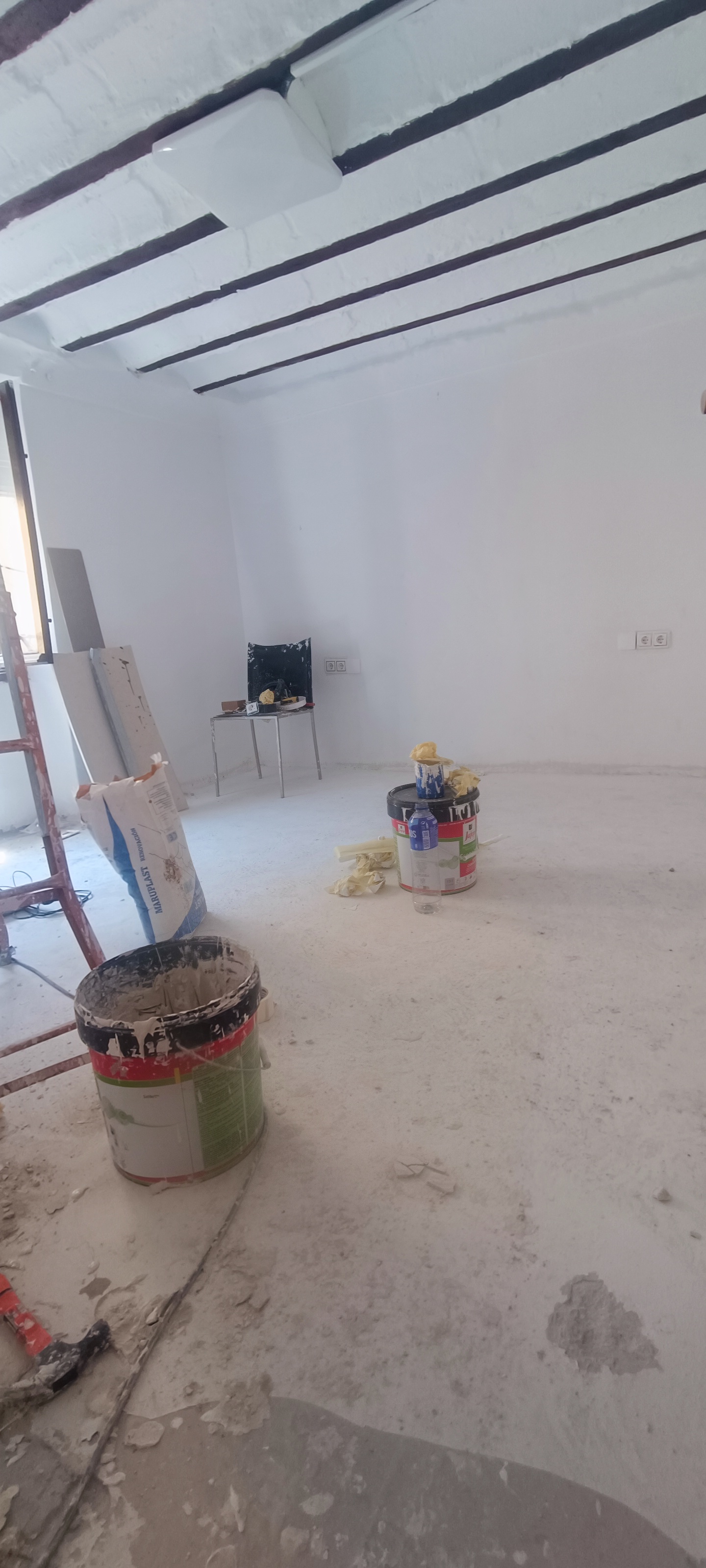 Habitación recién pintada con herramientas de obra y suelo protegido